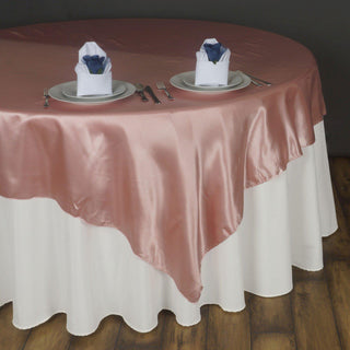 Elevate Your Event with the Dusty Rose Seamless Satin Square Table Overlay