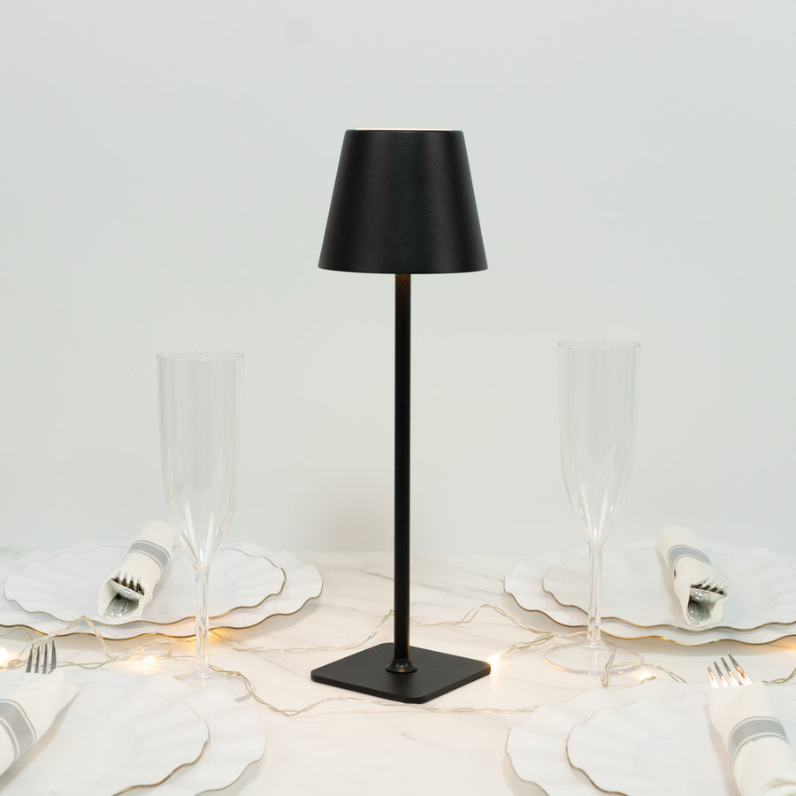 Black table lamp on a dining table with elegant dishware and glasses.