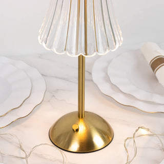 Gold table lamp with clear fluted glass shade on marble surface