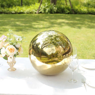 Gold decorative sphere on a table with flowers in an outdoor setting.