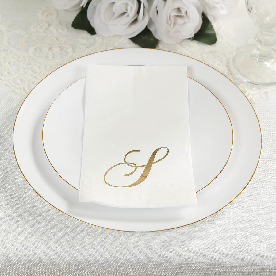 Elegant white plate with gold trim and personalized napkin on a textured tablecloth.