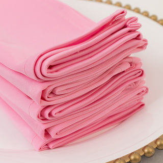 Stack of four folded pink napkins on a decorative plate.
