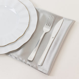 Elegant white plate with gold rim, silver cutlery on satin napkin.