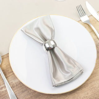 Elegant silver napkin with a metallic ring on a white plate.