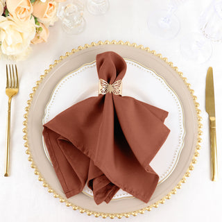 Elegant brown napkin with butterfly holder on a decorative plate.
