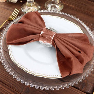 Elegant brown napkin on a decorative plate with a crystal napkin ring.