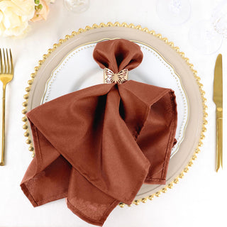 Brown napkin with butterfly ring on an elegant dinner plate.