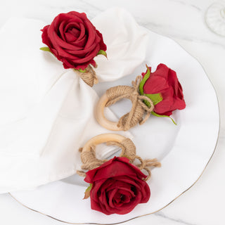 Rose napkin rings with wooden accents and twine on a white plate.