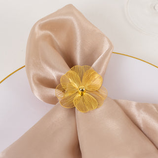 Elegant beige satin napkin tied with a yellow flower accent on a plate.