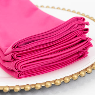 Stack of vibrant pink fabric rolls on a decorative plate.