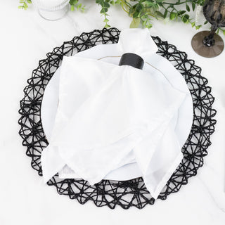 Elegant white napkin tied with a black ring on a decorative black placemat.