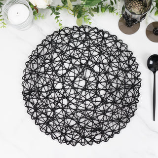 Black woven placemat on a marble surface with decorative elements around it.