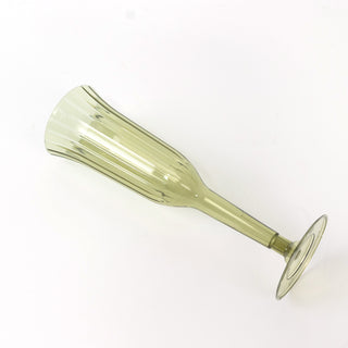 Green glass champagne flute on a plain background.