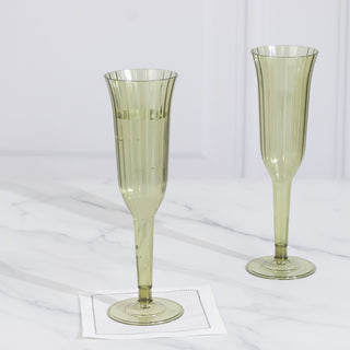 Two elegant green champagne flutes on a marble surface.