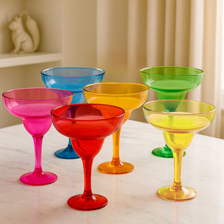 Colorful plastic margarita glasses in various hues on a marble surface.