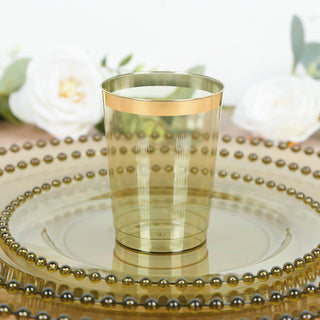 Gold-trimmed green plastic cup on decorative plate with floral elements in background.