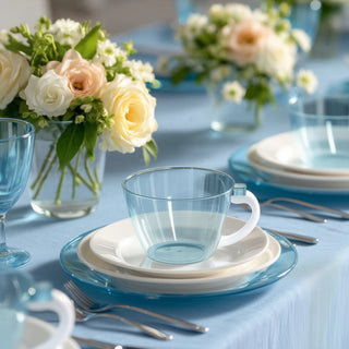 Elegant blue glass cup with white plates on a beautifully set dining table.