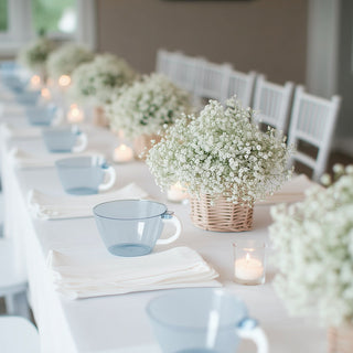 Elegant table setup with blue cups and floral arrangements for a serene gathering.