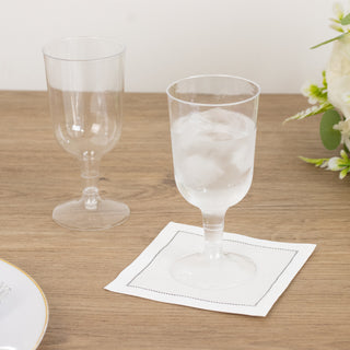 Two elegant glasses, one clear and one frosted, on a wooden table with a napkin.