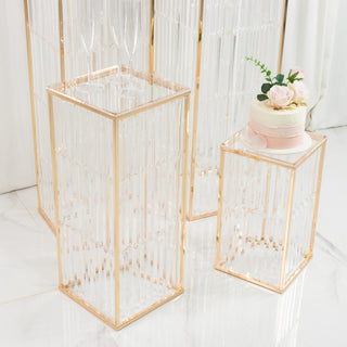 Elegant clear acrylic display pedestals with gold accents and floral cake decoration.