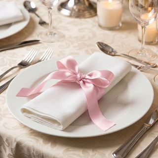 Elegant table setting with white napkin and pink ribbon on dinner plate