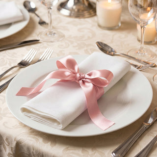 Elegant table setting with white plate, pink ribbon napkin, and candlelight