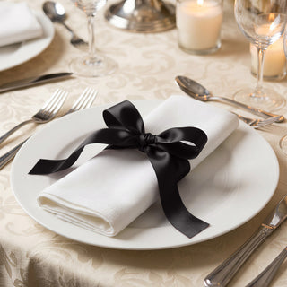 Elegant table setting with white napkin, black ribbon, and formal dinnerware
