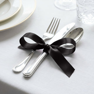 Elegant table setting with black ribbon tied around silver cutlery and utensils