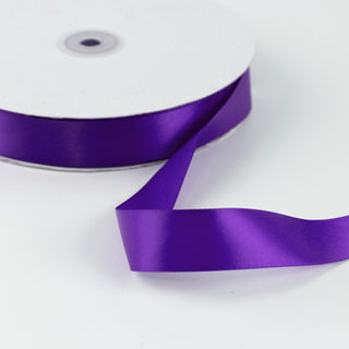 Purple satin ribbon spool on white background