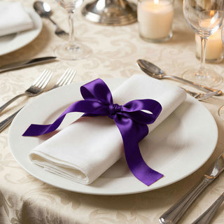 Elegant table setting with white napkin tied by purple ribbon on a dinner plate