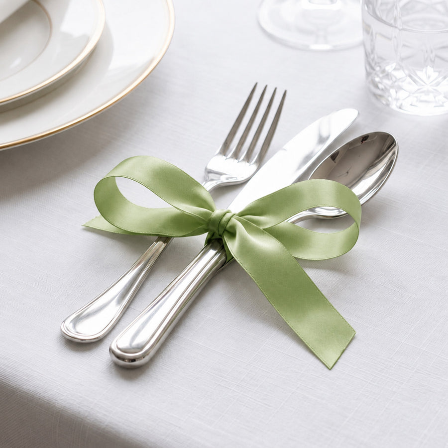 Elegant table setting with silver cutlery tied with green ribbon bow