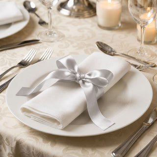 Elegant white dinner plate with satin ribbon napkin on formal table setting
