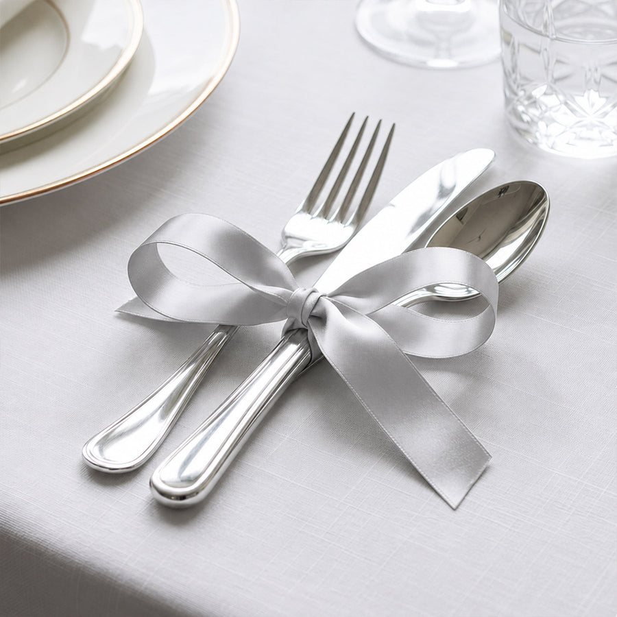 Elegant silver cutlery with white ribbon on a formal white table setting