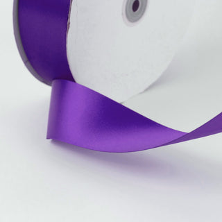 Purple satin ribbon close-up with white paper and grommet details