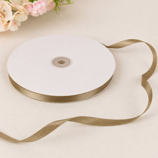 Gold satin ribbon spool on white background with floral accents