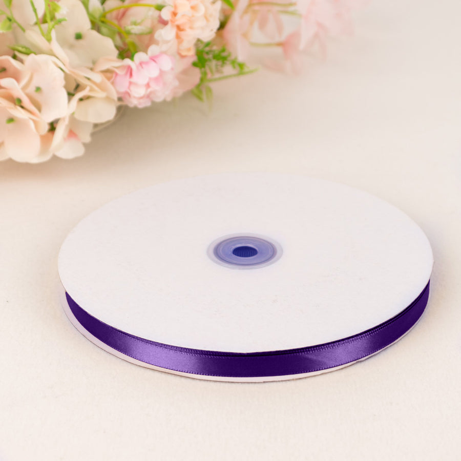 Purple satin ribbon spool on white table with soft floral background