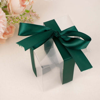 Clear gift box with green ribbon on a light background.