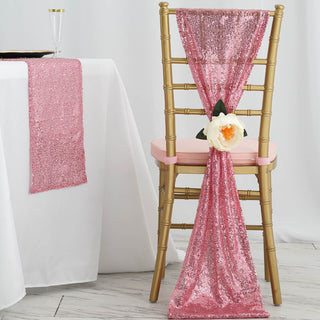 Pink sequin chair sash draped on a gold chair with a flower accent.