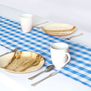 Table setting with plates, mugs, and utensils on a blue checkered tablecloth