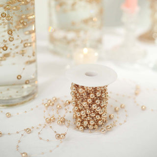 Gold decorative bead garland on a spool with blurred glass vases in the background.