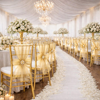 Elegant wedding venue with gold chairs, floral arrangements, and chandeliers.
