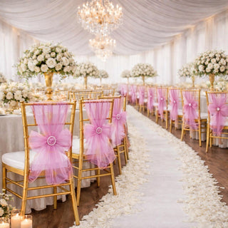 Elegant wedding reception with gold chairs and pink bows, adorned with floral arrangements.