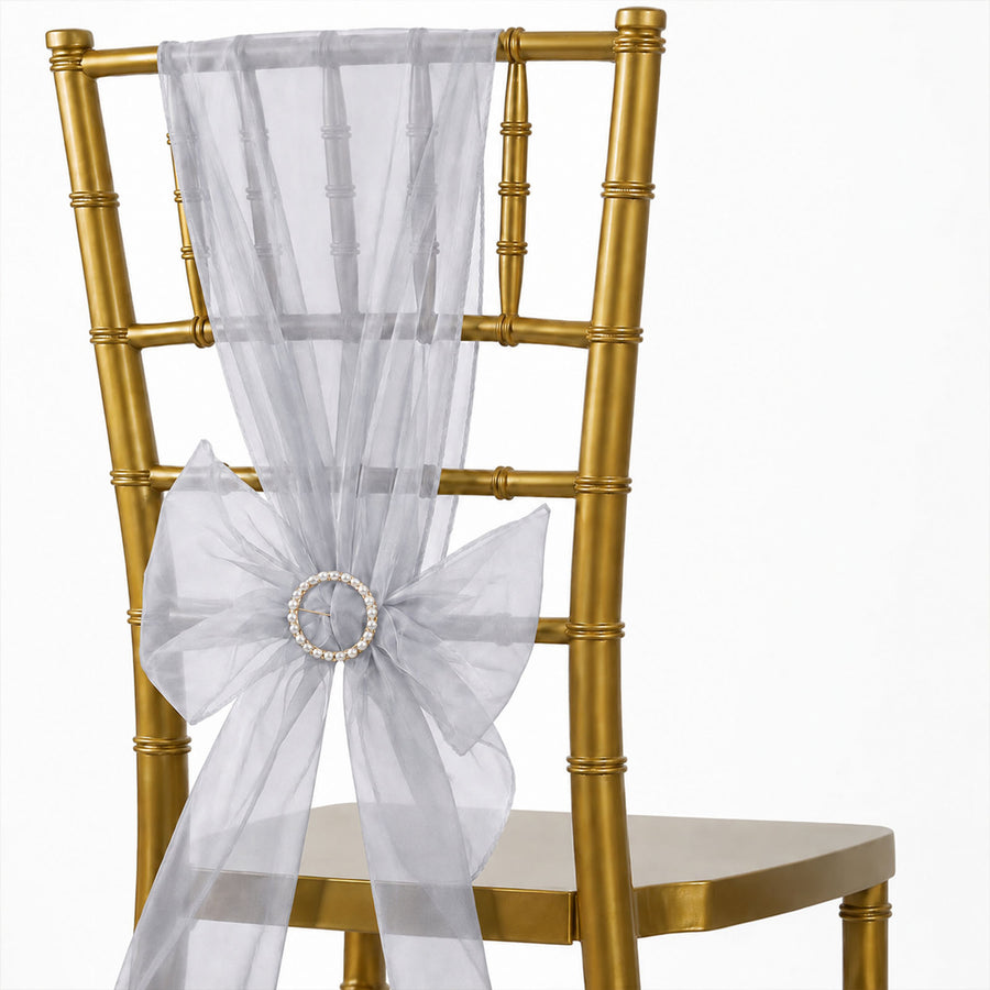 Gold chiavari chair with white sheer organza sash and pearl brooch decoration