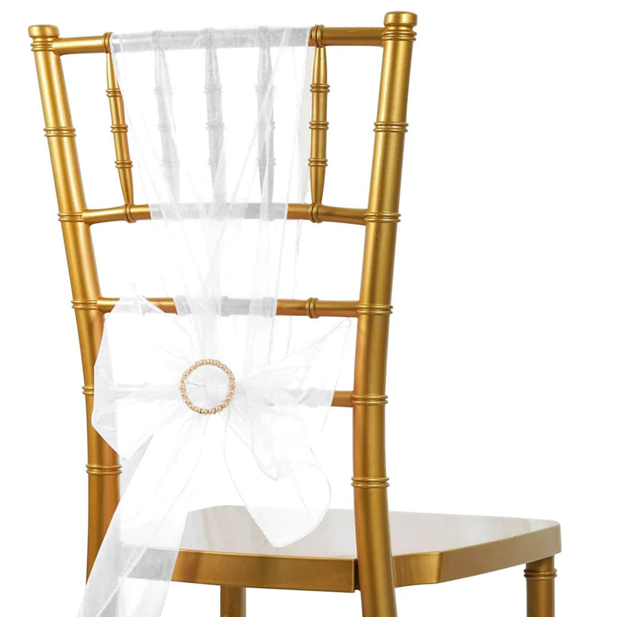 Gold chiavari chair with white sheer ribbon and decorative ring.