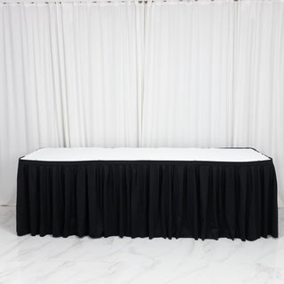 Black skirted banquet table with white top against white curtains