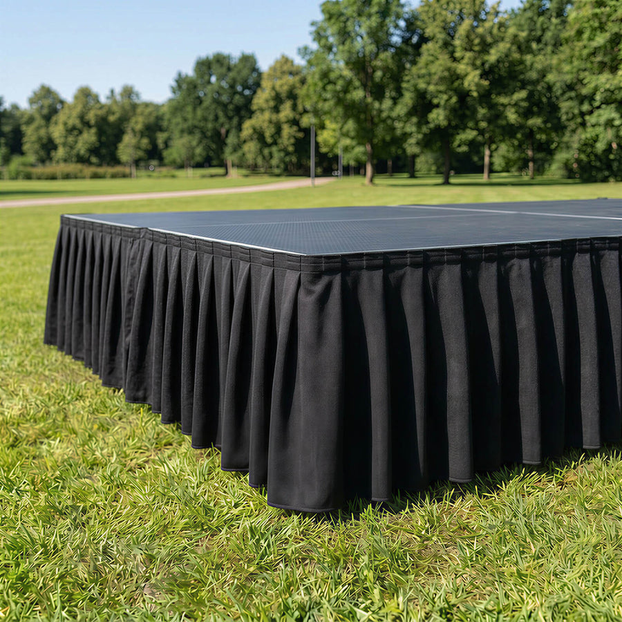 Black stage skirt on outdoor platform in a park setting
