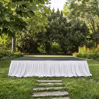 Outdoor garden stage with white draped skirting and lush greenery background