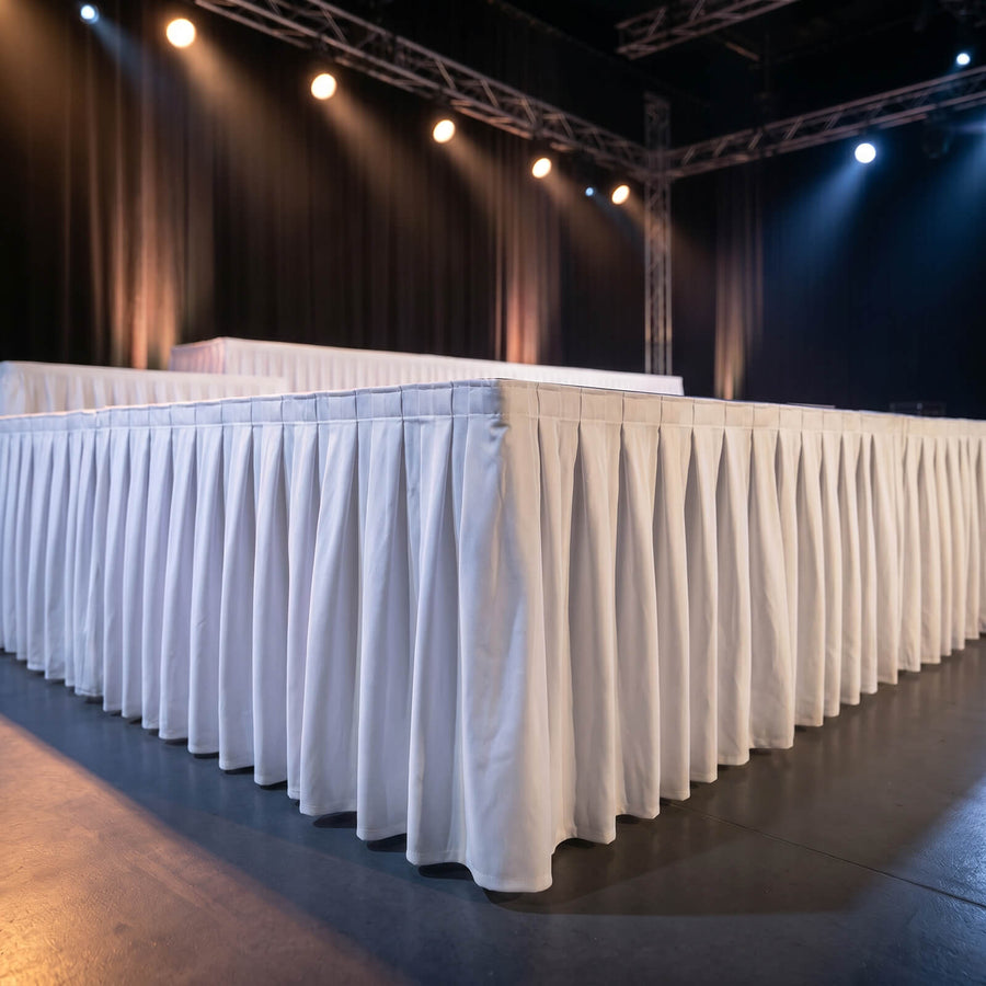 Empty event stage with draped tables and spotlighted truss lighting