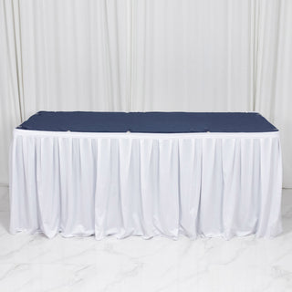 White banquet table with navy tablecloth and white skirting on studio backdrop