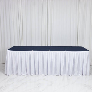White skirted banquet table with navy tabletop against a white draped backdrop